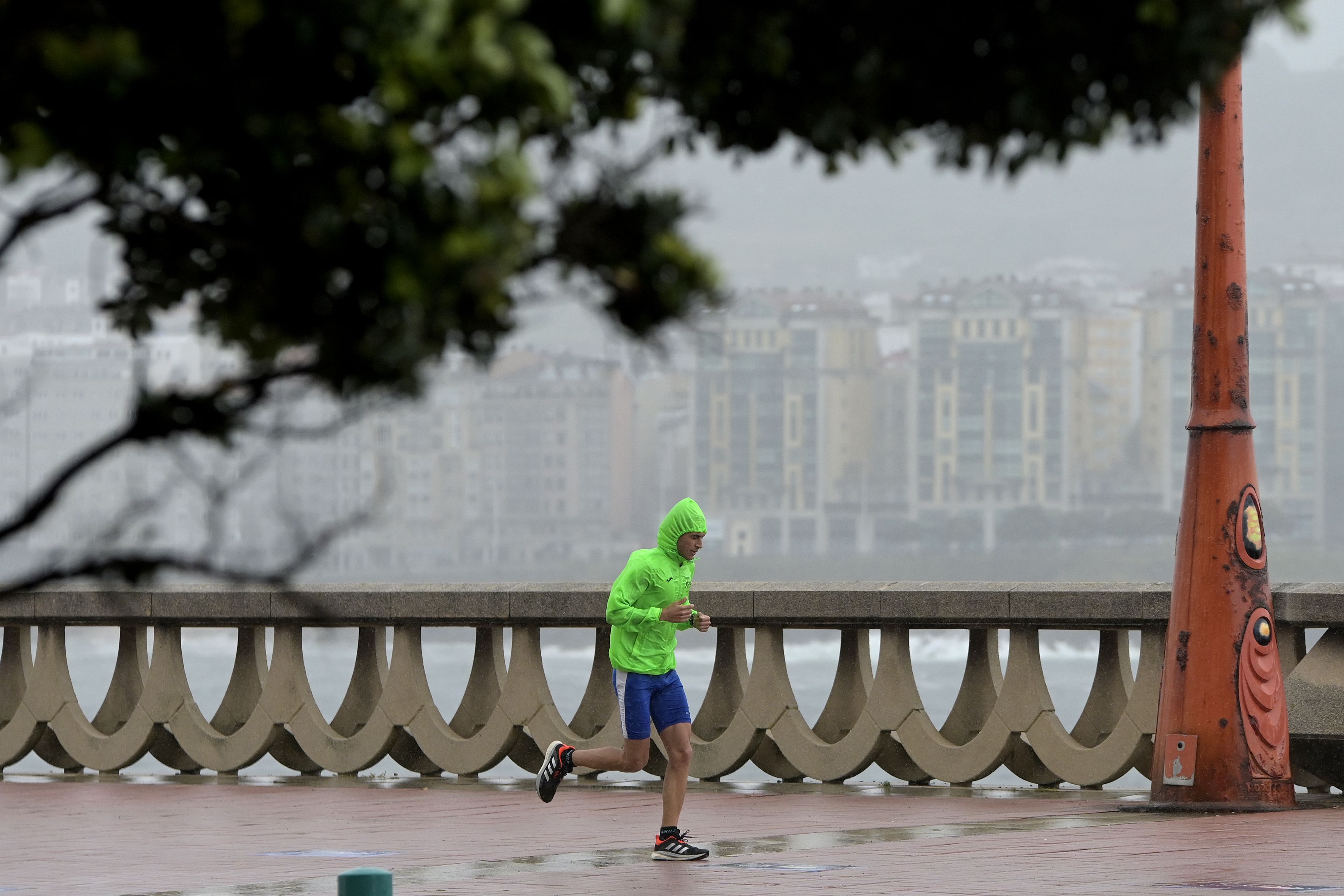 man wearing a rain jacket runs along the paseo maritimo in news photo