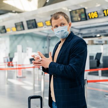 man wearing mask cleaning hands at airport