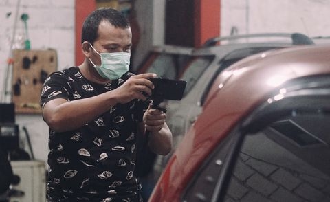 man wearing mask photographing car