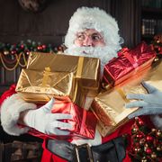man wearing santa claus costume holding christmas presents at home