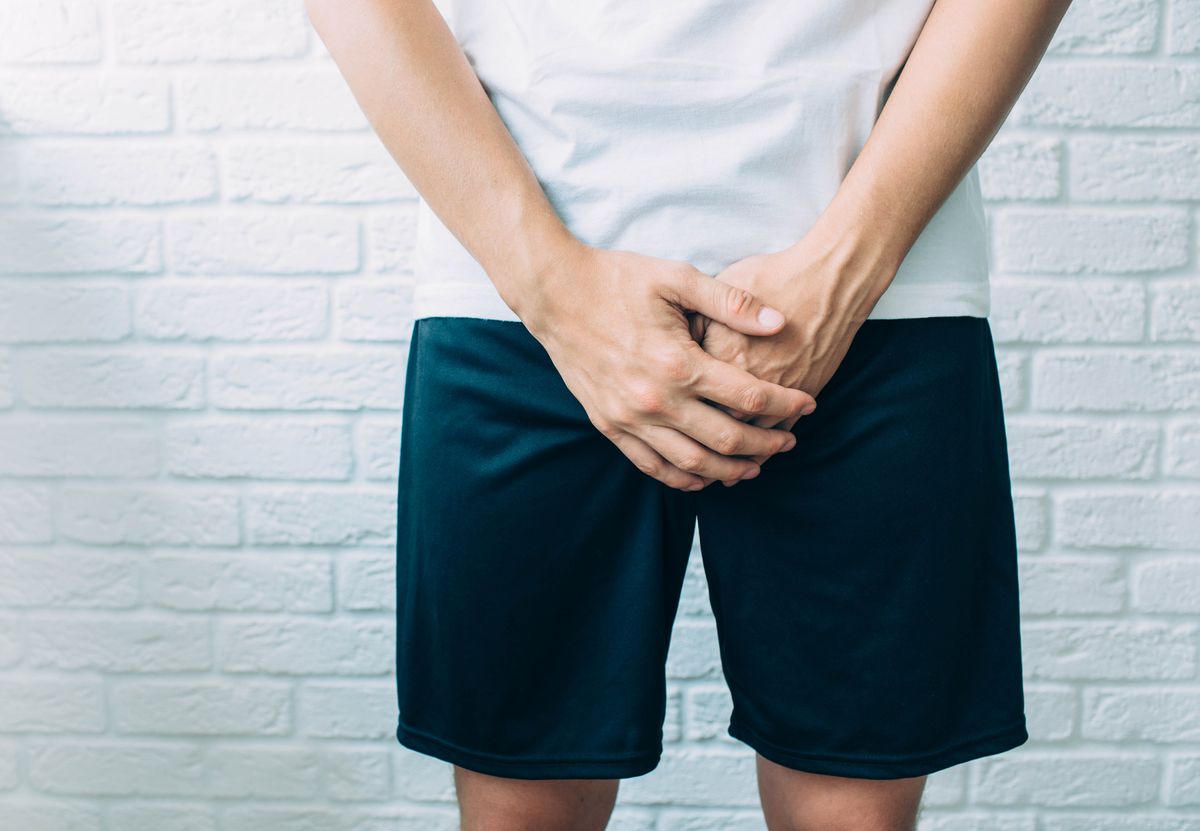 man wearing shorts holding genitals men's health, venereologist, sexual disease