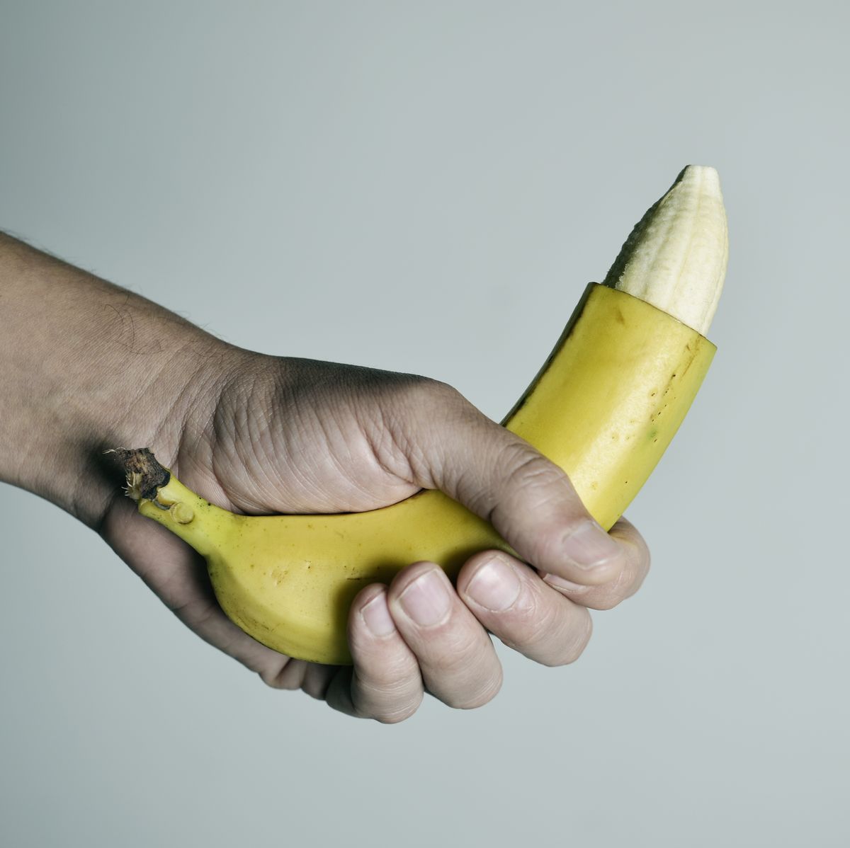 man with a banana with the tip of its skin removed