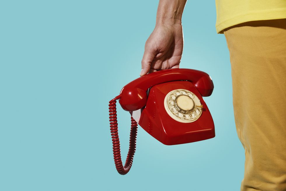 man with an old red telephone in his hand