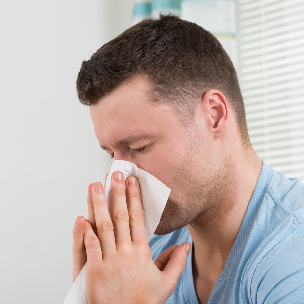 man with cold blowing his nose at home