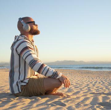 man with headphones sitting at the beach