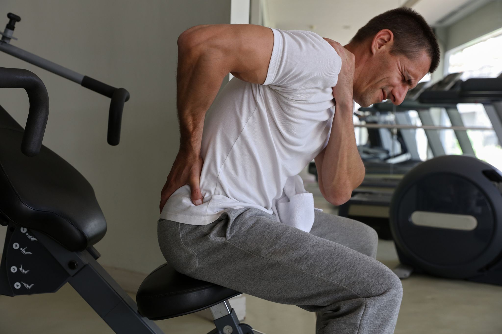Man with low back pain in gym. Sports exercising injury