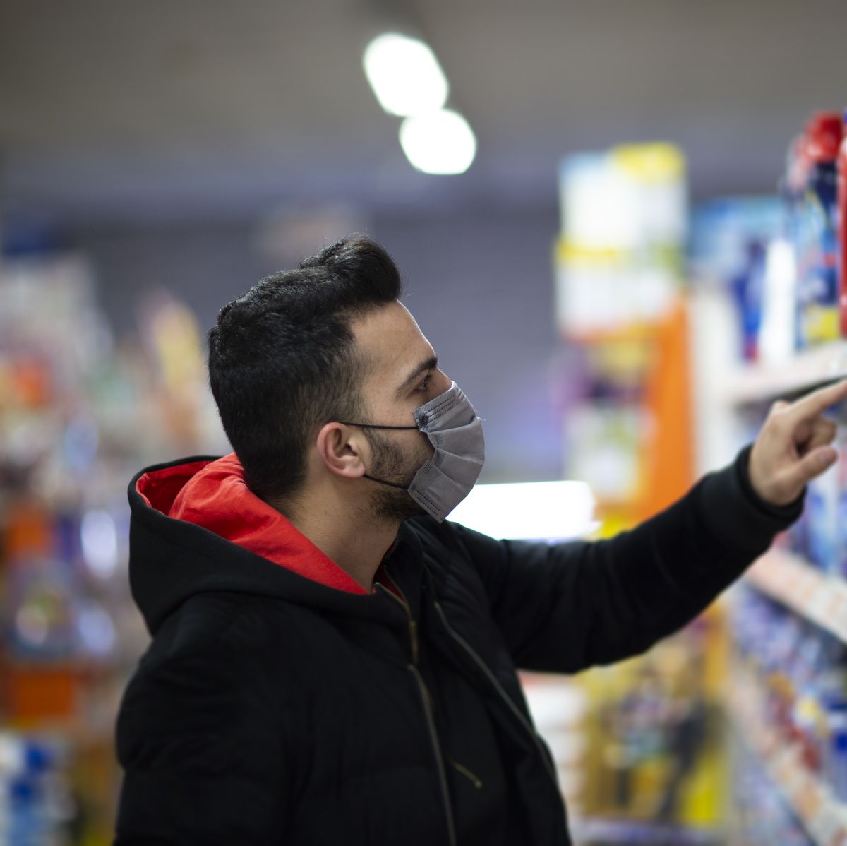 man with the mask on his face at the supermarket is looking for a disinfectant
