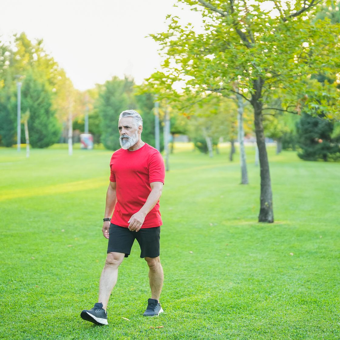 man with white hair and red t shirt walking in the park