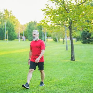 man with white hair and red t shirt walking in the park