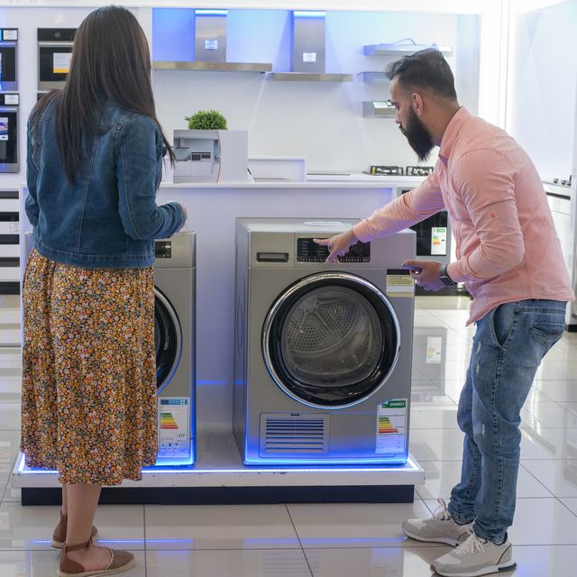 a man woman comparing two washing machines in an appliance store