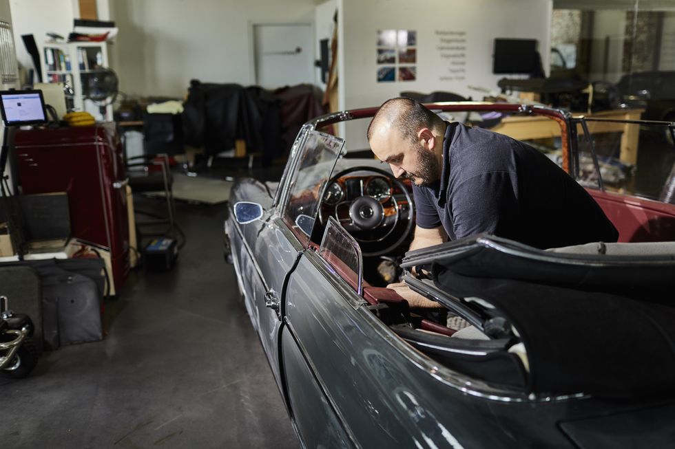 man working on vintage car in an automobile upholstery workshop