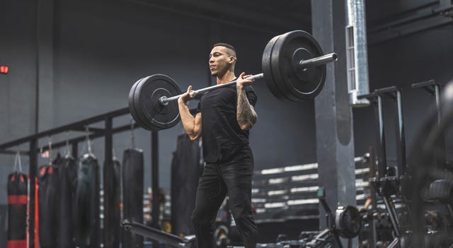 hombre haciendo ejercicio en un gimnasio con barra y pesas