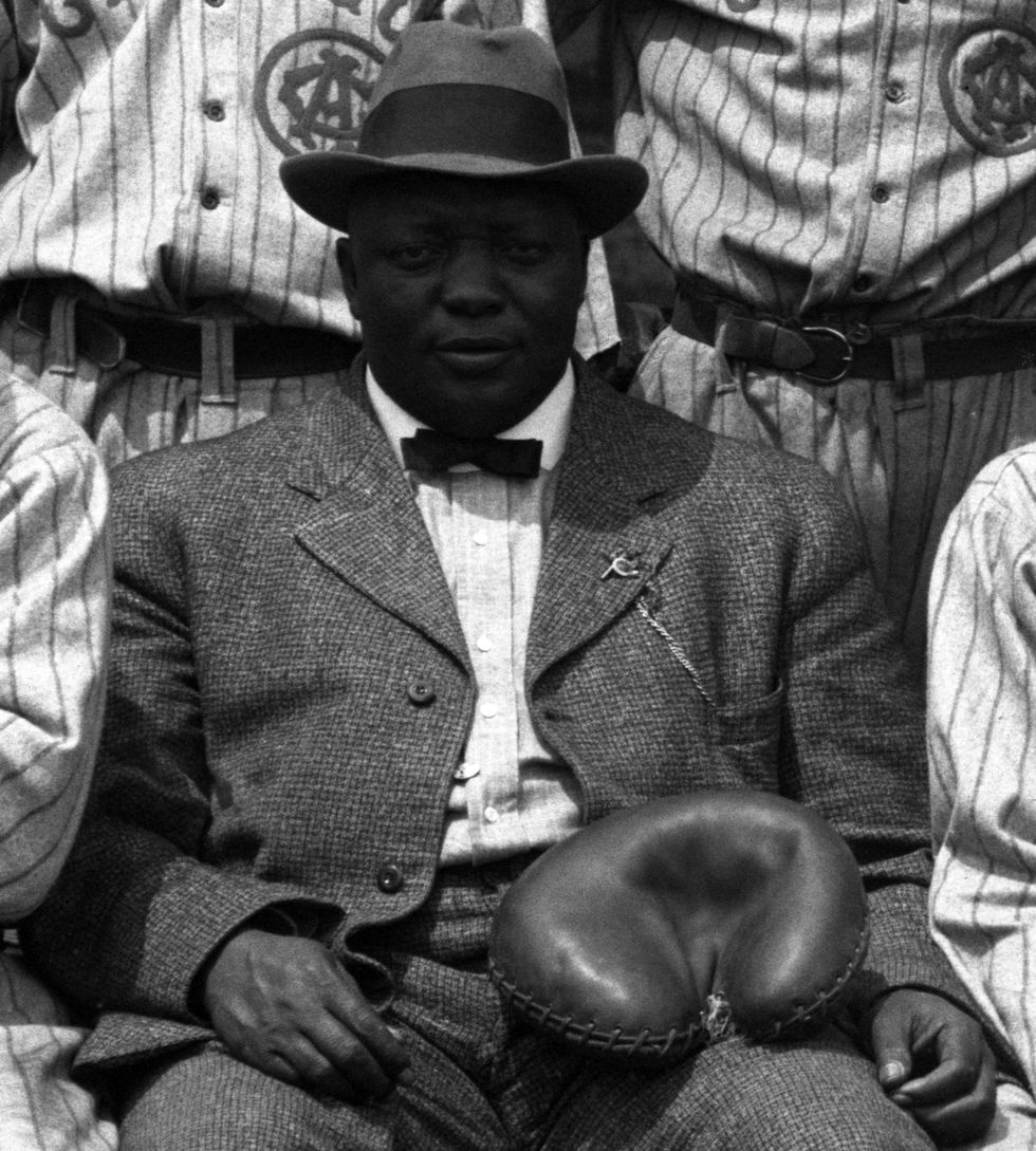rube foster sitting for a photograph with a glove on his thigh
