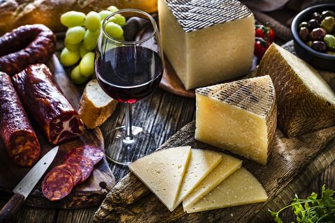 Spanish food: Manchego cheese, spanish chorizo and red wine on rustic wooden table