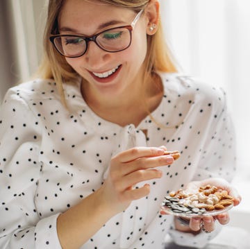 jonge vrouw eet noten van een schaaltje