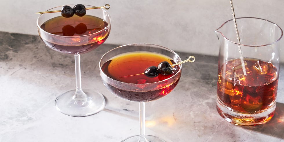 manhattan cocktail in a coupe glass garnished with dark cherries