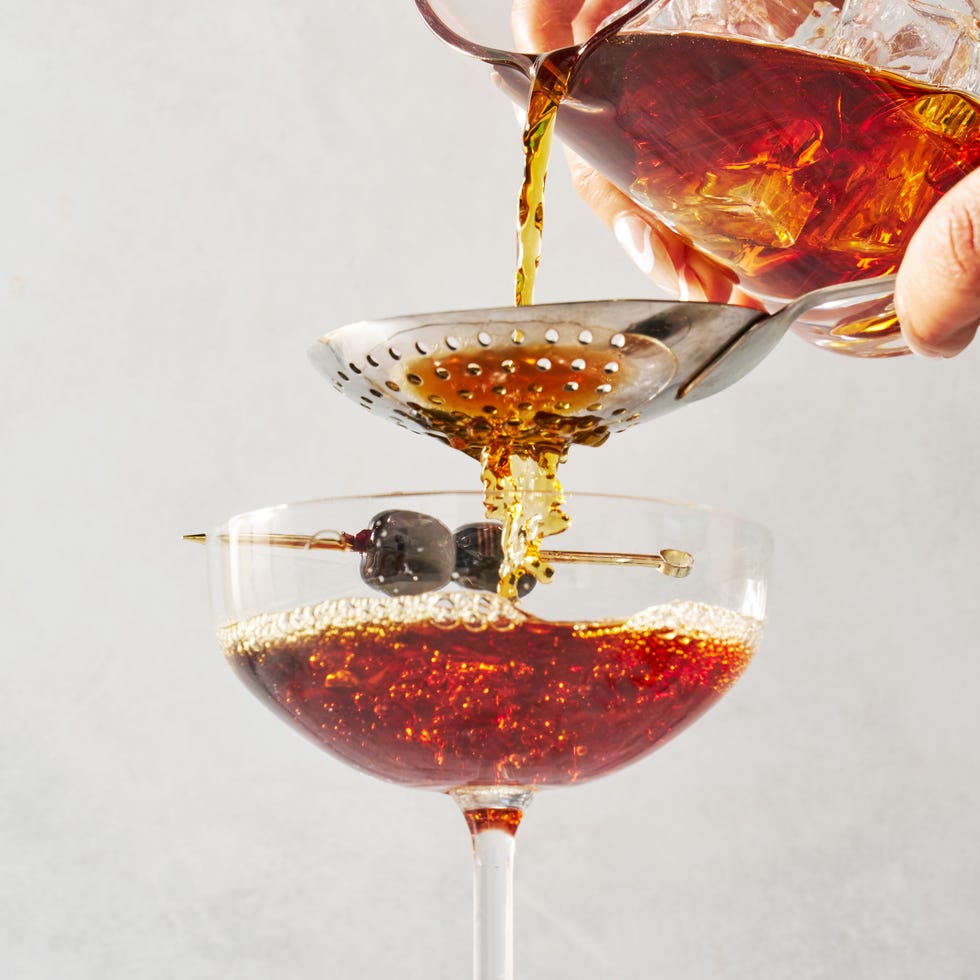 manhattan cocktail in a coupe glass garnished with dark cherries