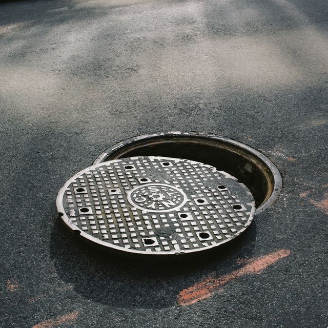 A manhole cover partially removed, close-up