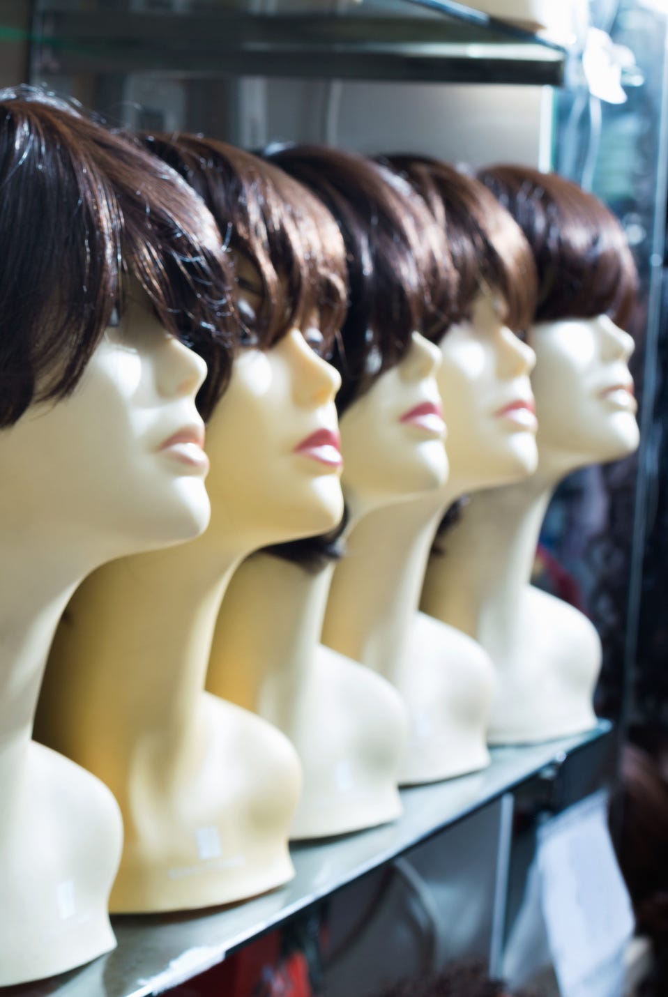 mannequins with brown haired and brunet style wigs on shelves