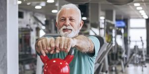 senior man in gym working out using kettle bells