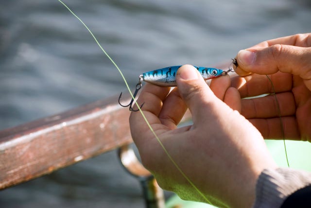 man's hand fixing bait on hook, elevated view