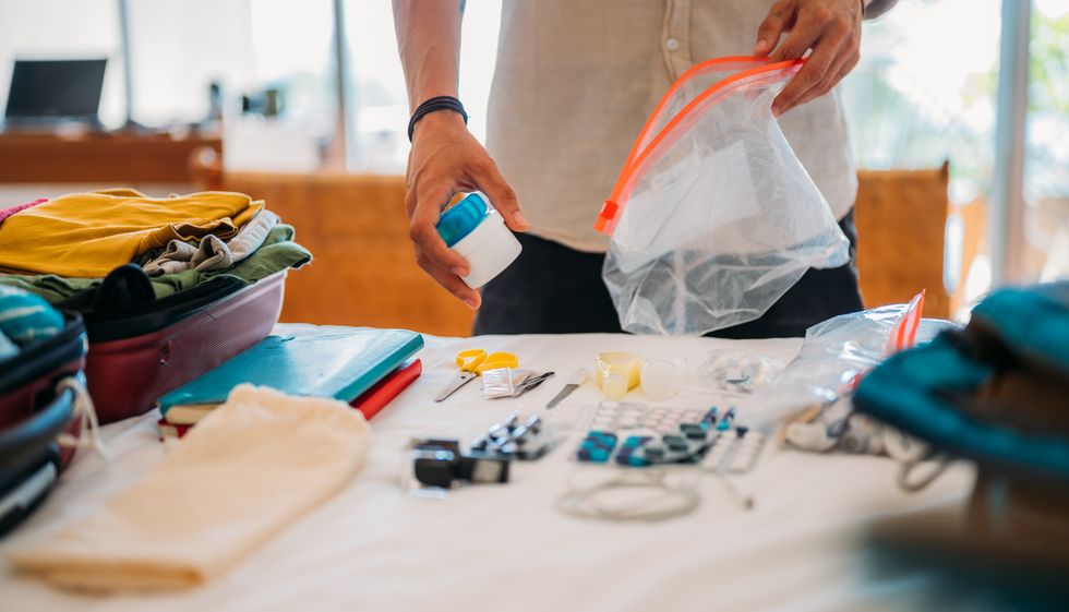 a man's hand packs cosmetics and medicines for the trip in a bag with a zipper.