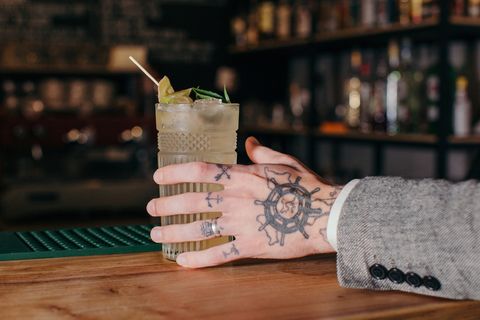 mans hand reaching for a cocktail in a bar