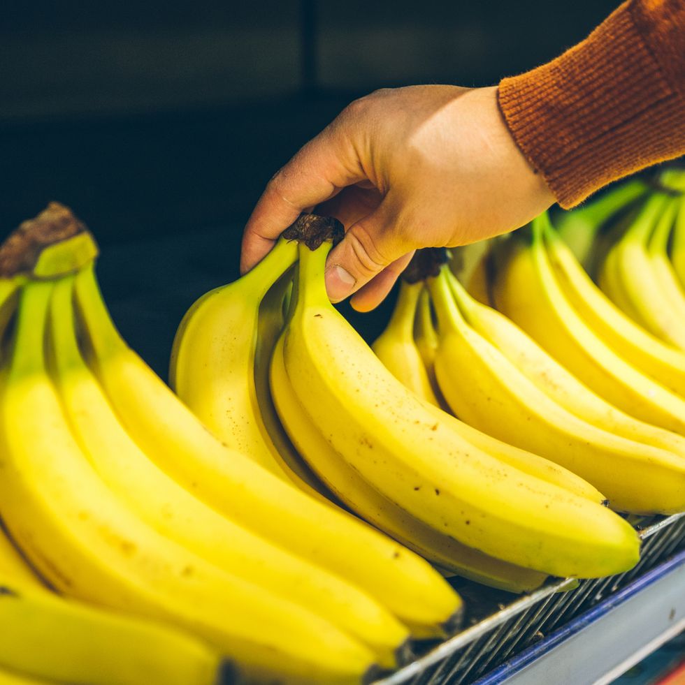 mans hand take bananas from shelf of store. healthy food. shopping concept