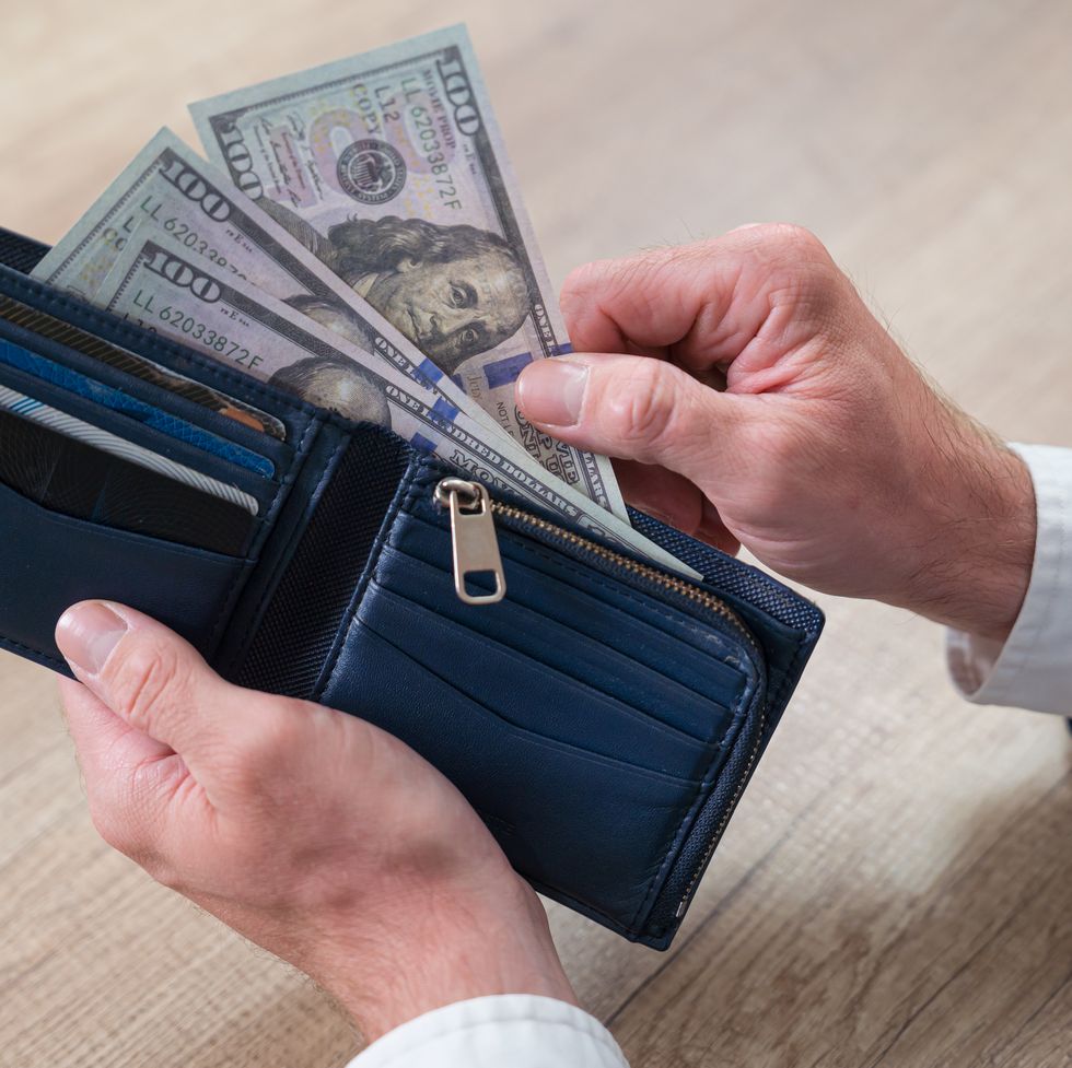 man's hands holding wallet and american dollar banknotes.