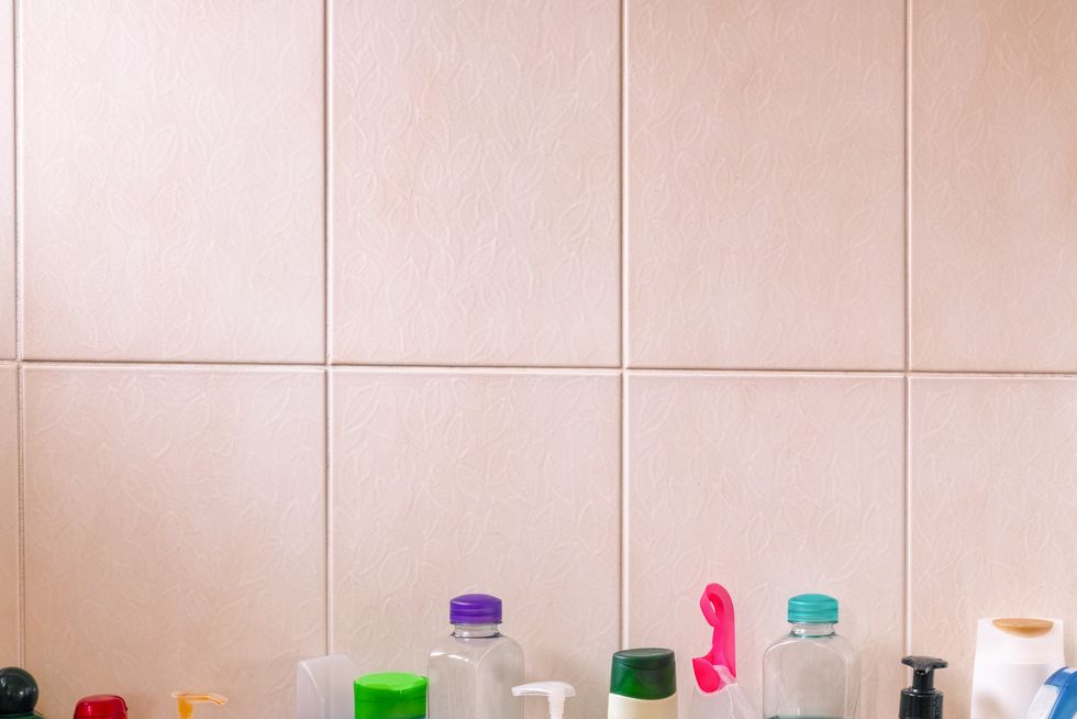 many shampoo and soap bottles on a bathroom shelf.