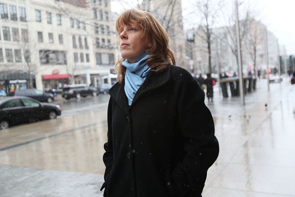 manya chylinski, wearing a black coat and blue scarf, looking up on the streets of boston
