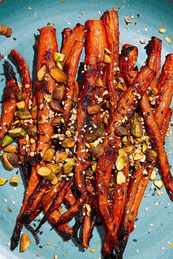 miso roasted carrots topped with pistachios and black and white sesame seeds on a teal plate