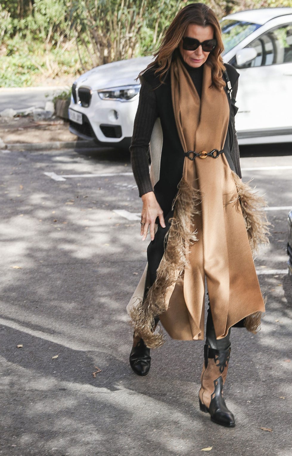 a person walking on a parking lot wearing a stylish outfit with a decorative scarf