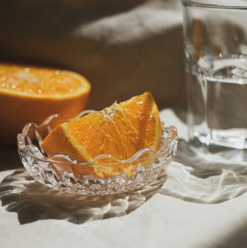 a glass of water next to a peeled orange