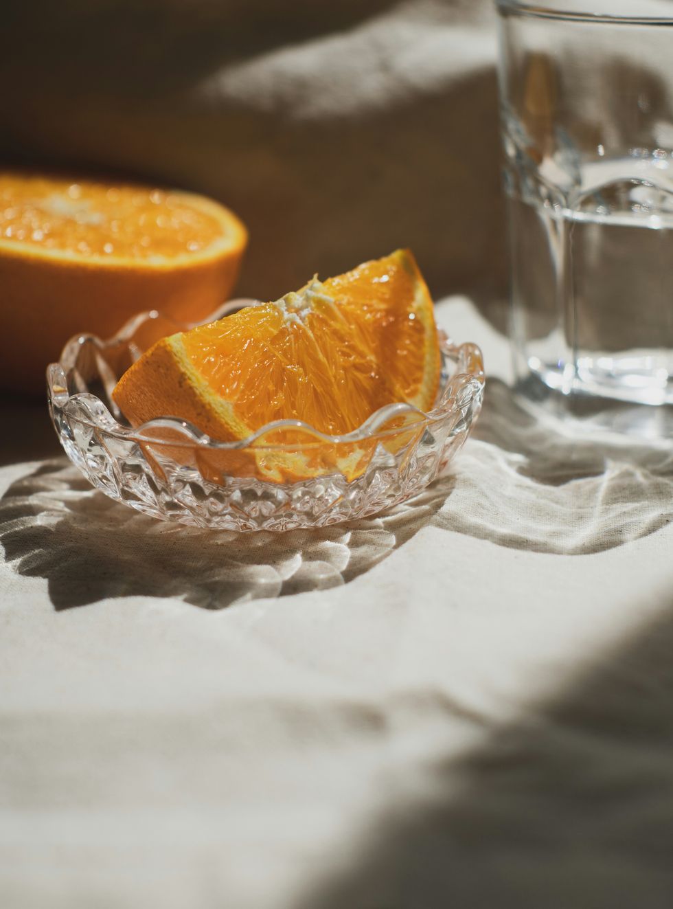 a glass of water next to a peeled orange