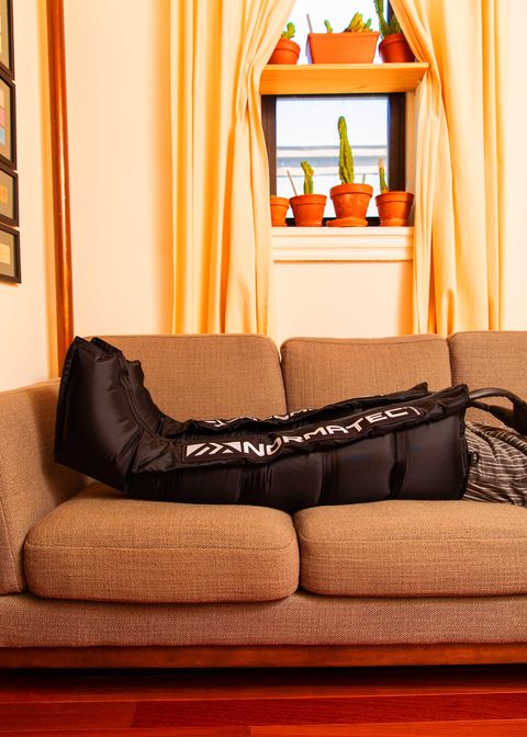 Runner in Normatec pants on couch in living room.