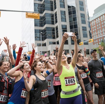 Marathon runners posing, waving and cheering for selfie at starting line on urban street Marathon runners posing, waving and cheering for selfie at starting line on urban street