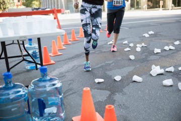 Marathon runners rounding corner with paper cups on street