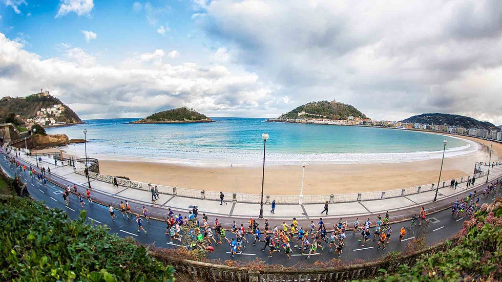 varios corredores en la maratón de donosti por delante de la playa de la concha