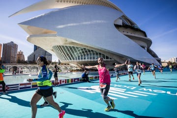 Participants running in a marathon with a modern architectural building in the background