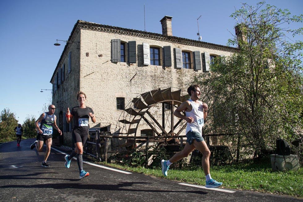 runners participating in a race near a historical building with a water wheel