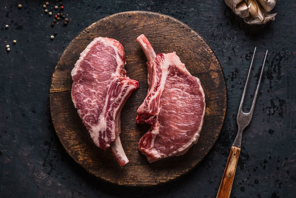 marbled raw pork chops of porco iberico meat on round cutting board with meat knife