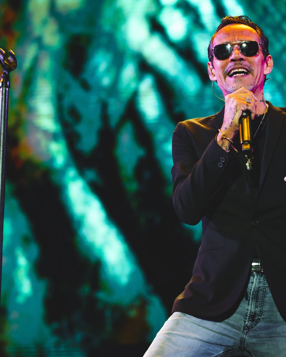 a man wearing sunglasses sings into a wireless microphone