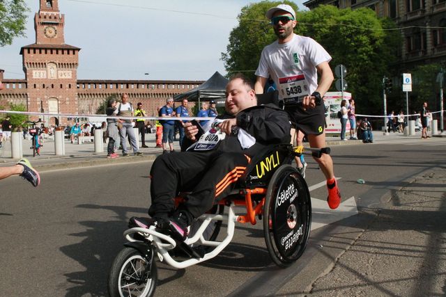 a man in a wheelchair running with a man in a wheelchair