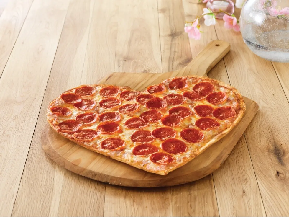 heartshaped pizza with pepperoni slices on a wooden board