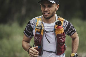 el ultrarunner Marcos Yánez corriendo por un camino portando un chaleco con dos botellas de agua. 