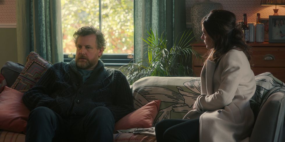 Marcus Garvey als Eddie Walker und Michelle Keegan als Maya Stern sitzen zusammen auf einem Sofa in „Fool Me Once“ von Netflix