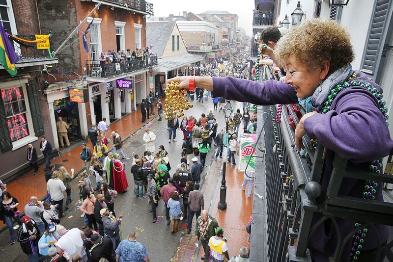 woman throwing beads from balcony