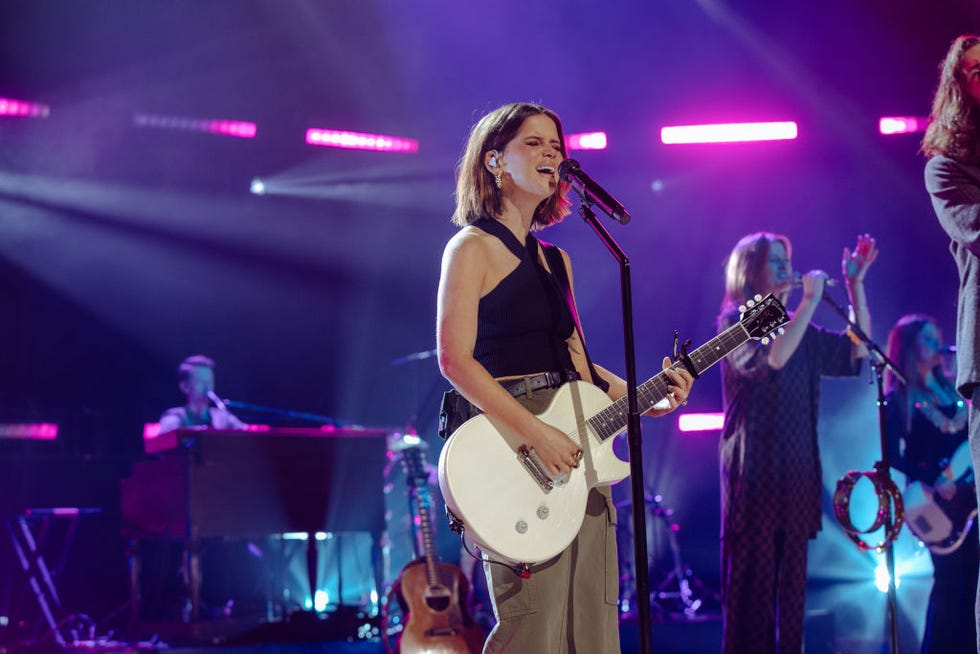 maren morris holding a guitar and singing on stage
