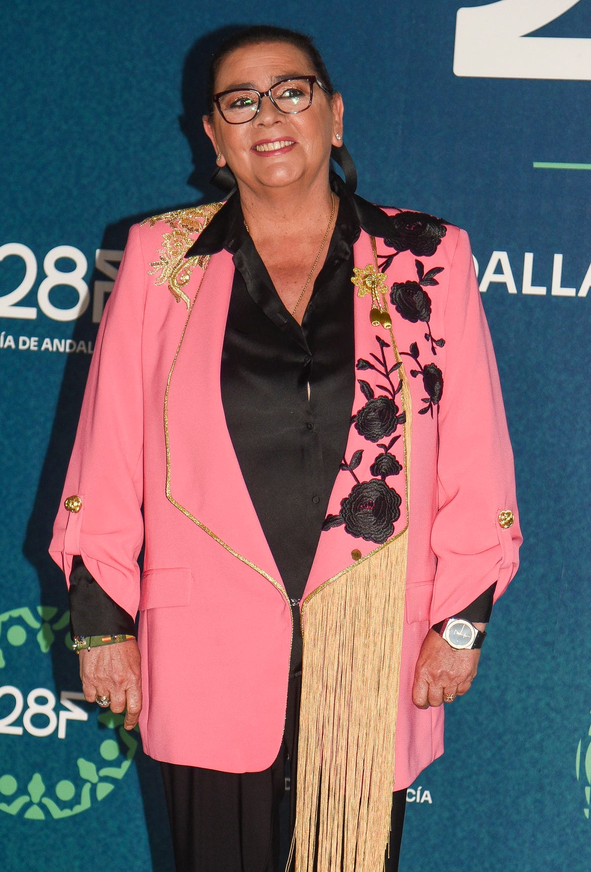 la cantante con una chaqueta rosa con detalles de flores y flecos